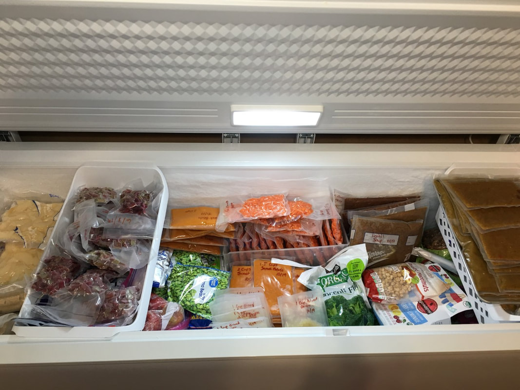 A chest freezer filled to the top with vacuumed sealed garden produce and other food. 