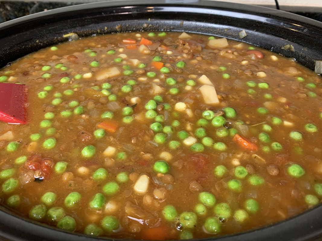 Crockpot full of potato lentil soup with green peas and corn