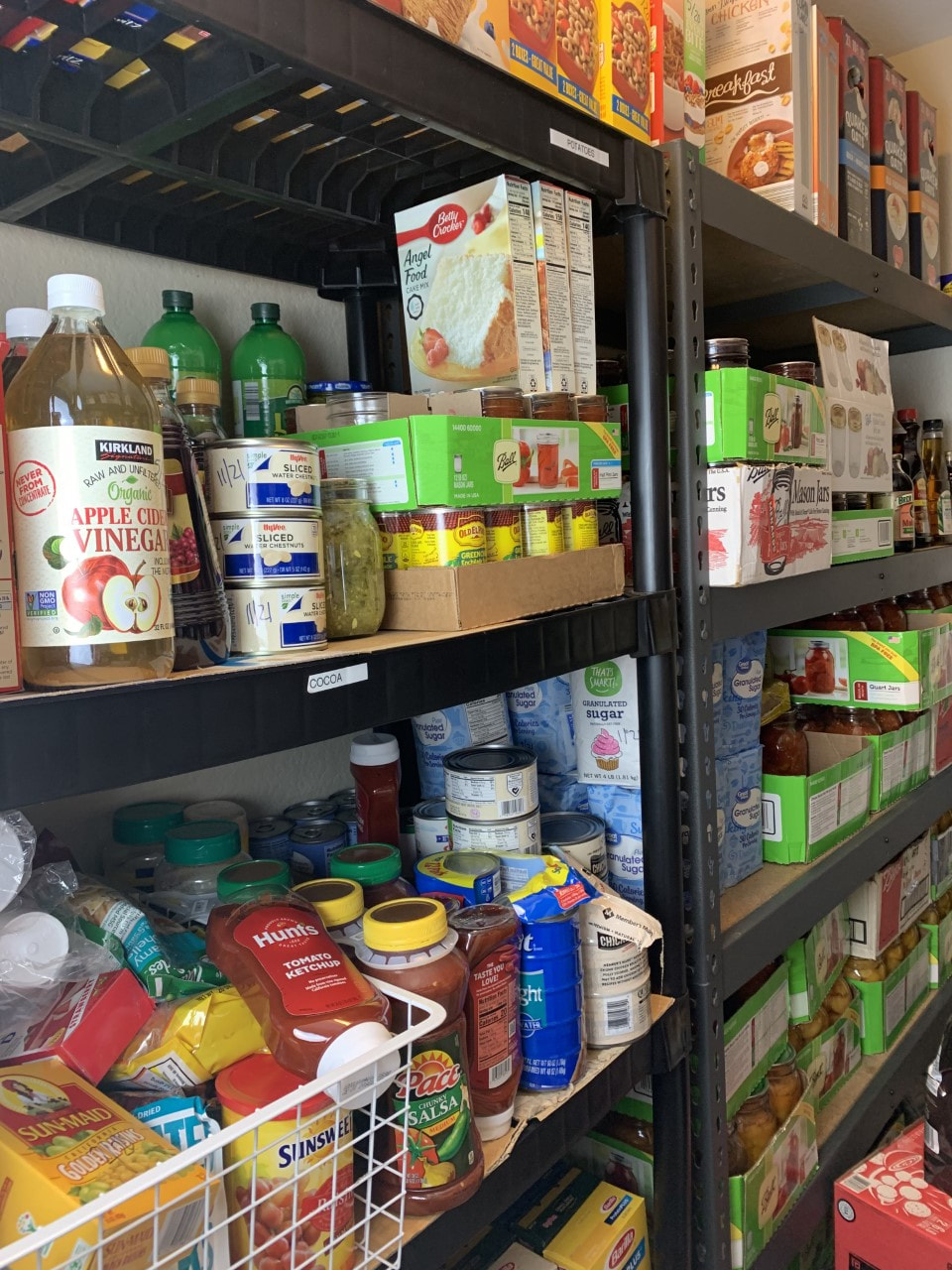 Basement pantry lined with shelves filled with non-perishable food and canned food.